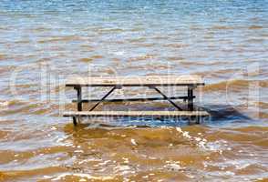 Empty picnic table in muddy brown water