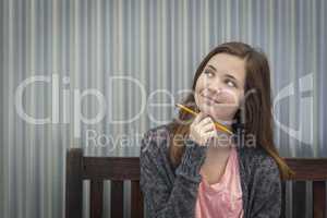 Young Daydreaming Female Student With Pencil Looking to the Side