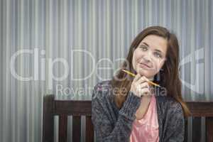 Young Daydreaming Female Student With Pencil Looking to the Side