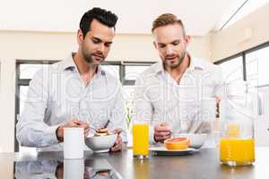 Unsmiling gay couple couple having breakfast