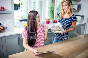 Upset woman showing dirty dishes to friend