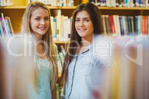 Smiling students standing together near bookshelves