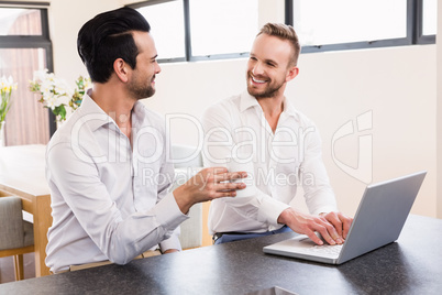 Smiling gay couple using laptop