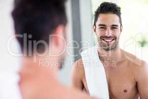 Handsome shirtless man looking in the mirror