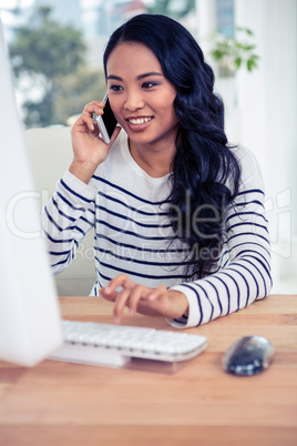 Smiling Asian woman on a phone call using computer