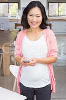 Smiling pregnant woman using smartphone