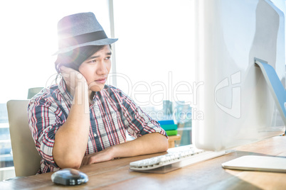 Worried hipster businessman using computer