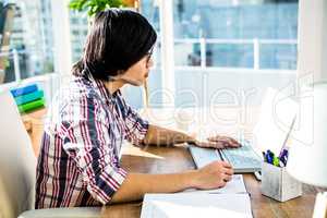 Hipster businessman writing while using laptop