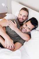 Happy gay couple lying on bed