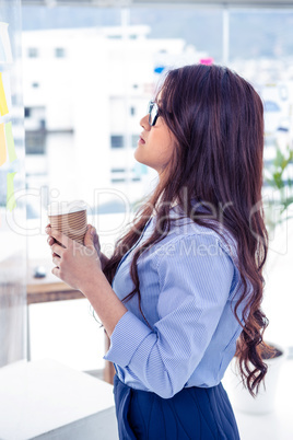 Businesswoman holding disposable cup and looking at wall with no