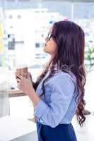 Businesswoman holding disposable cup and looking at wall with no