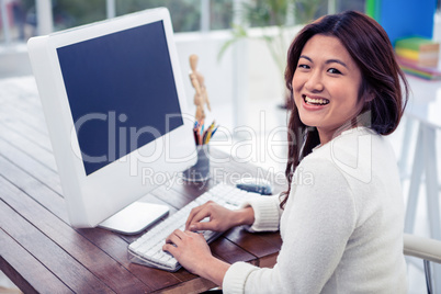 Smiling Asian woman on computer looking back at the camera