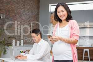 Smiling pregnant woman using smartphone
