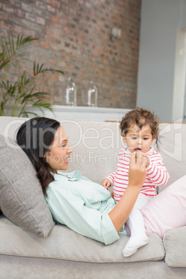 Smiling brunette playing with her baby