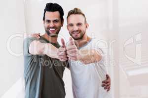 Smiling gay couple showing thumbs up