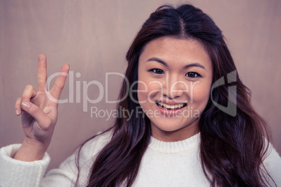Smiling Asian woman making peace sign