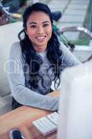 Smiling Asian woman using computer and looking at the camera