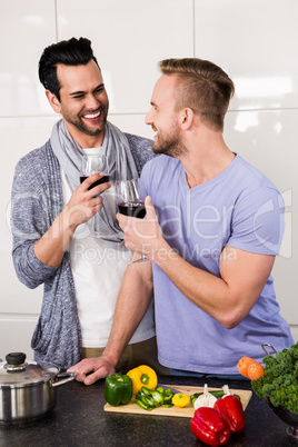 Smiling gay couple with red wine