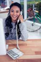 Smiling Asian woman on phone call looking at the camera