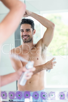 Handsome man using spray deodorant