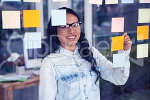 Asian woman writing on sticky notes