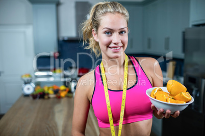 Fit woman showing a bowl of oranges