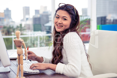 Smiling Asian woman on computer looking at the camera