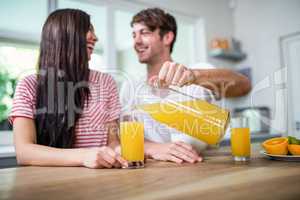 Handsome man pouring orange juice in a glass