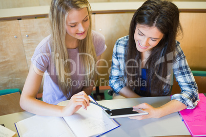 Two smiling students using tablet