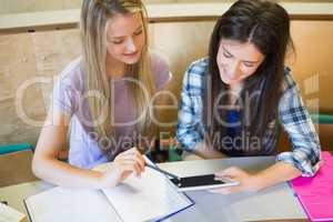 Two smiling students using tablet