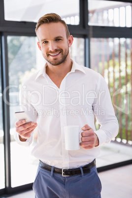 Smiling man with mug and smartphone Smiling man with mug and smartphone