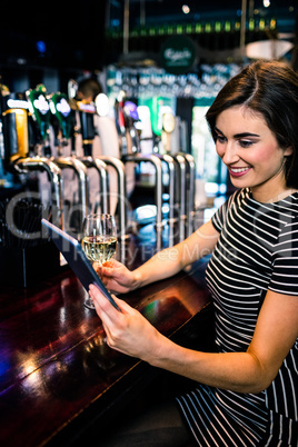 Woman using tablet and having a glass of wine