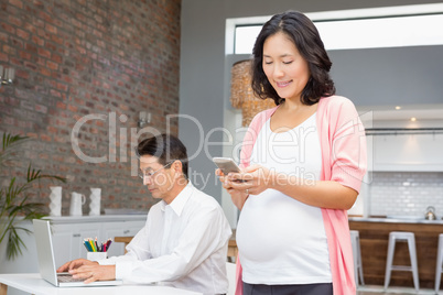 Smiling pregnant woman using smartphone