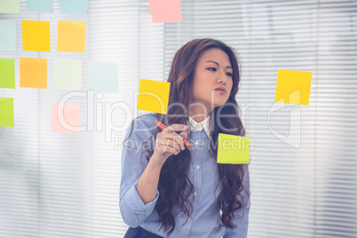 Asian businesswoman using sticky notes on wall