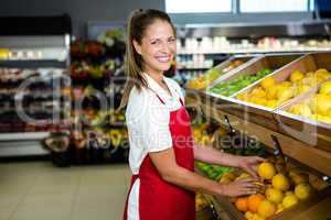 Smiling female worker stocking lemons