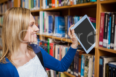 Female student tidying a tablet in a bookshelf