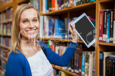 Female student tidying a tablet in a bookshelf