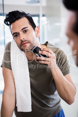 Handsome man using electric razor