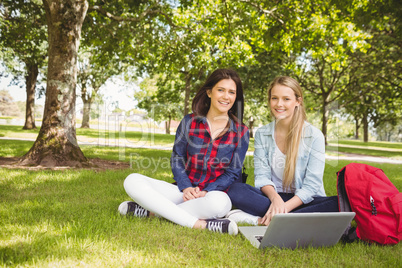 Smiling students using laptop