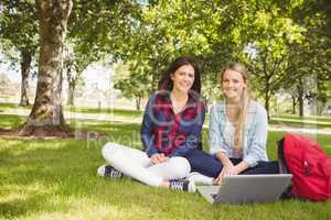 Smiling students using laptop