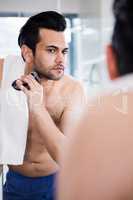 Handsome man shaving in the mirror