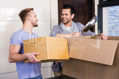 Smiling gay couple unpacking cardboard