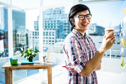 Smiling creative businessman with take-away coffee