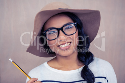 Smiling Asian woman with hat holding pencil