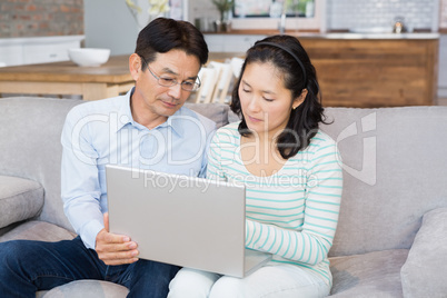 Serious couple using laptop