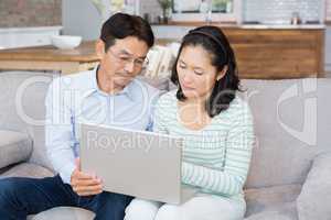 Serious couple using laptop