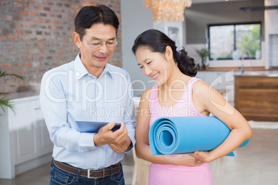 Happy couple using tablet and holding mat