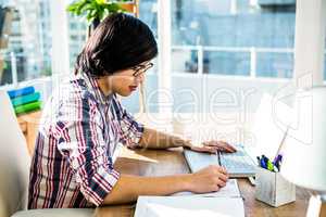 Hipster businessman writing while using laptop