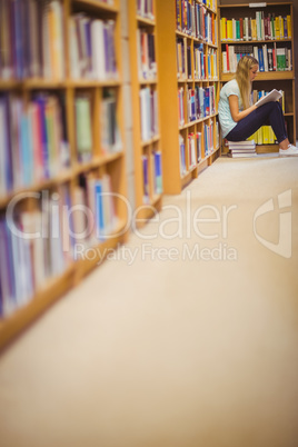 Blonde student reading while sitting on books