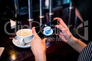 Woman taking a picture of coffee with smartphone